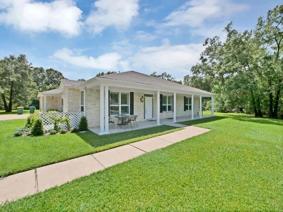 Covered rear porch opening onto a lawn