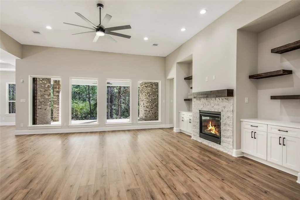 Light-filled living room with a fireplace, built-in cabinetry, and wood flooring